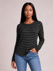 Model poses in a black and charcoal striped round neck long sleeve T-shirt with a relaxed silhouette and subtle slit detail at the hem.