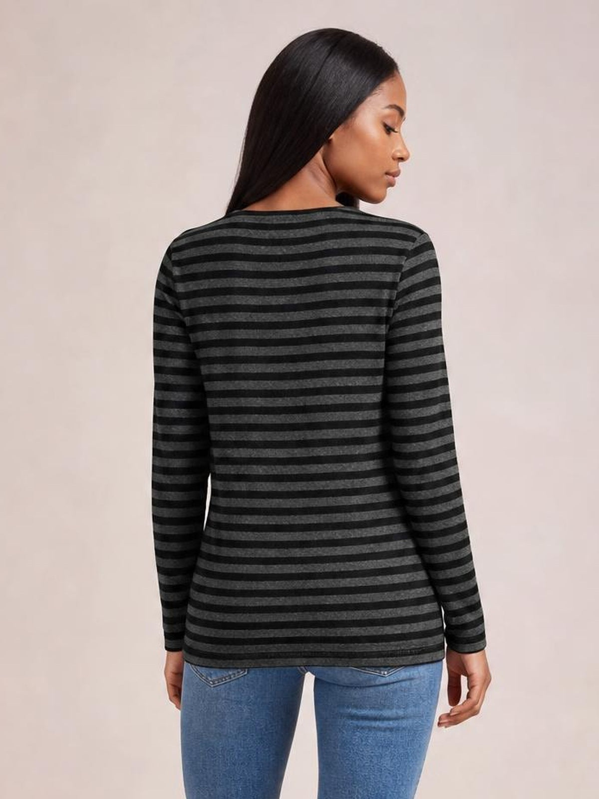 A model shown from behind wears a charcoal and black striped round-neck long-sleeve T-shirt with a relaxed, straight silhouette and opaque construction.