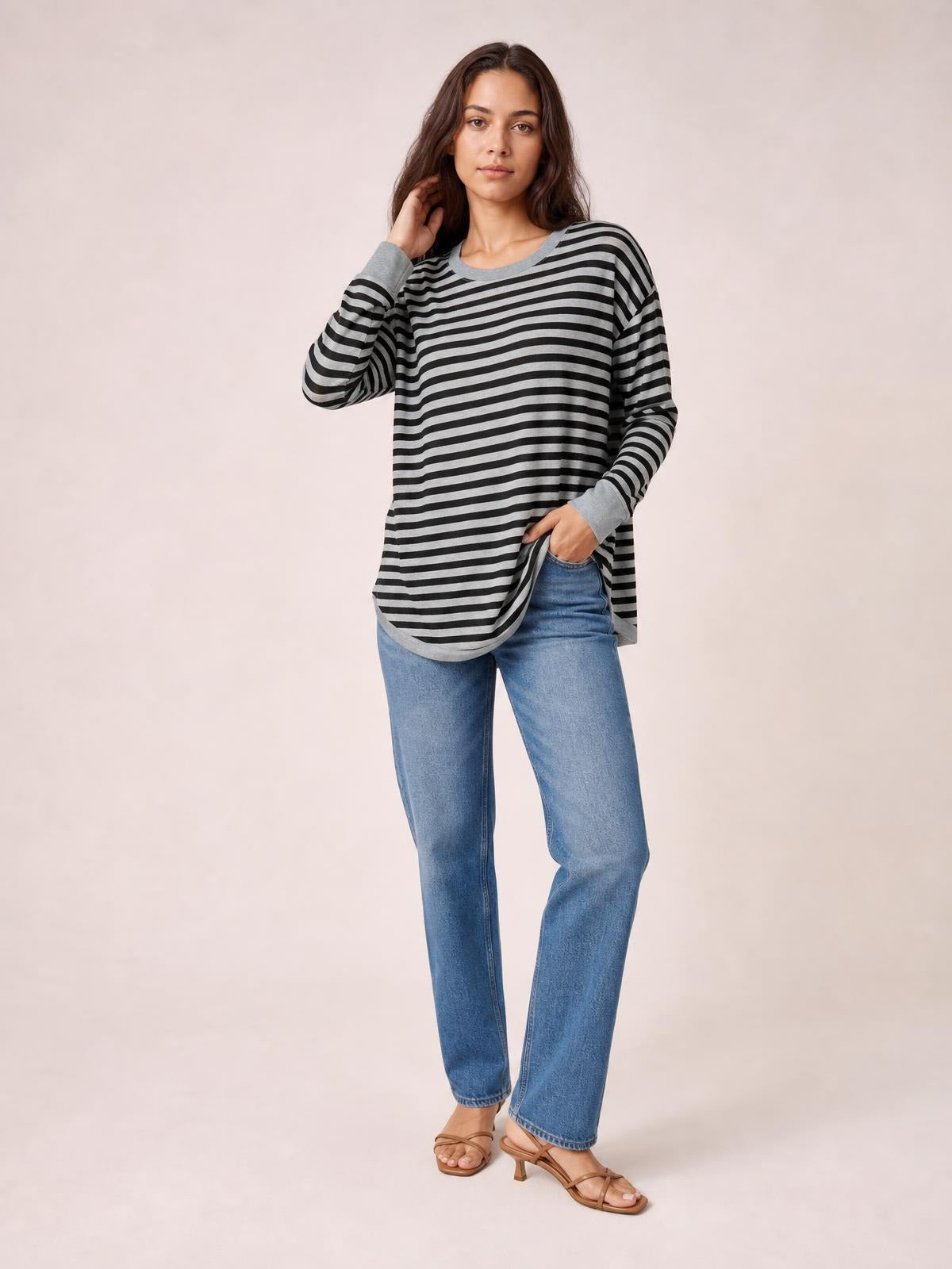 Model poses in a black-and-gray striped round neck long sleeve T-shirt with contrasting cuffs, relaxed loose silhouette, and visible side slit detail.