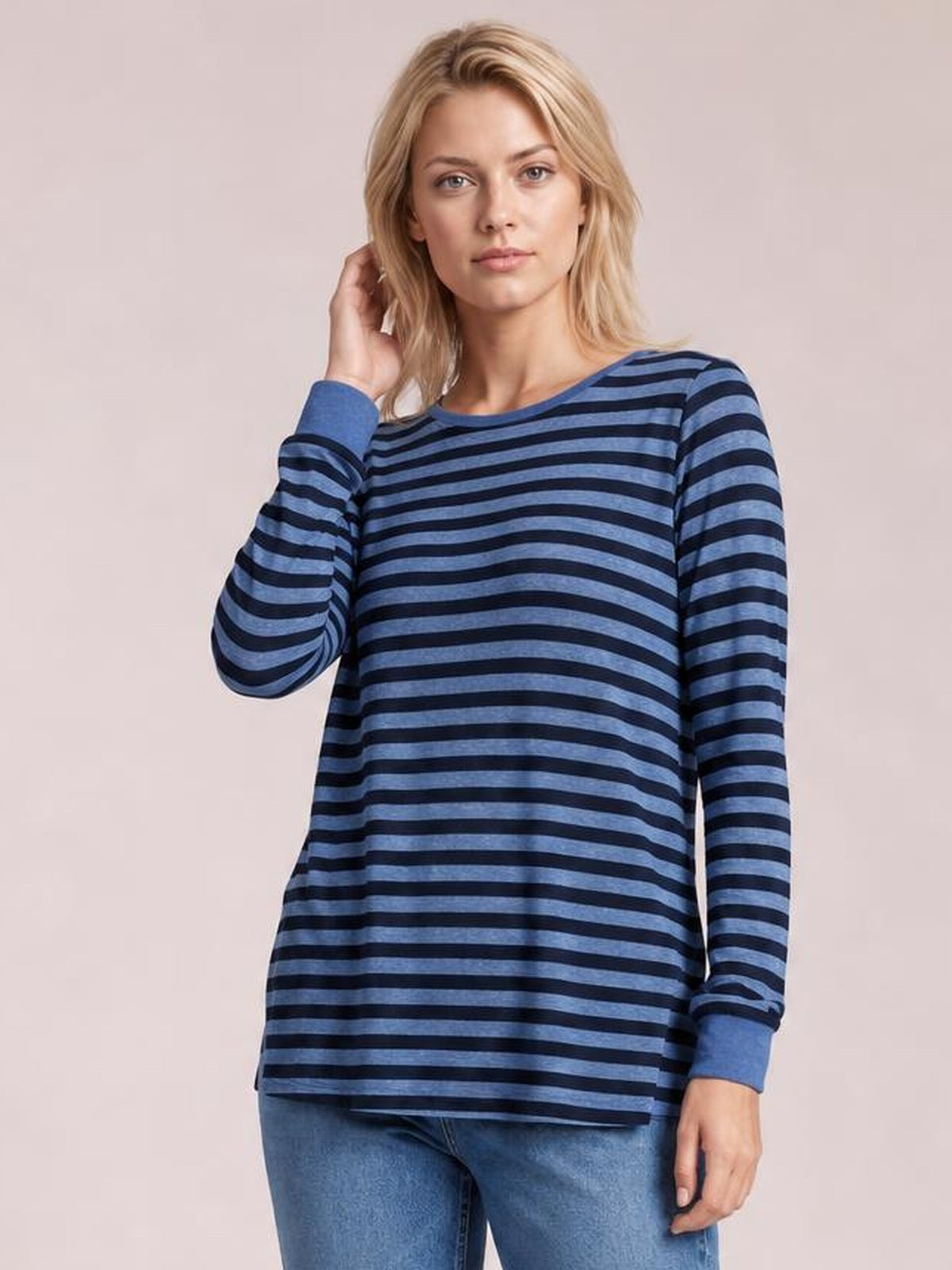 Model poses in a blue and navy striped round neck long sleeve T-shirt with a relaxed silhouette, ribbed cuffs, and side slit detail.