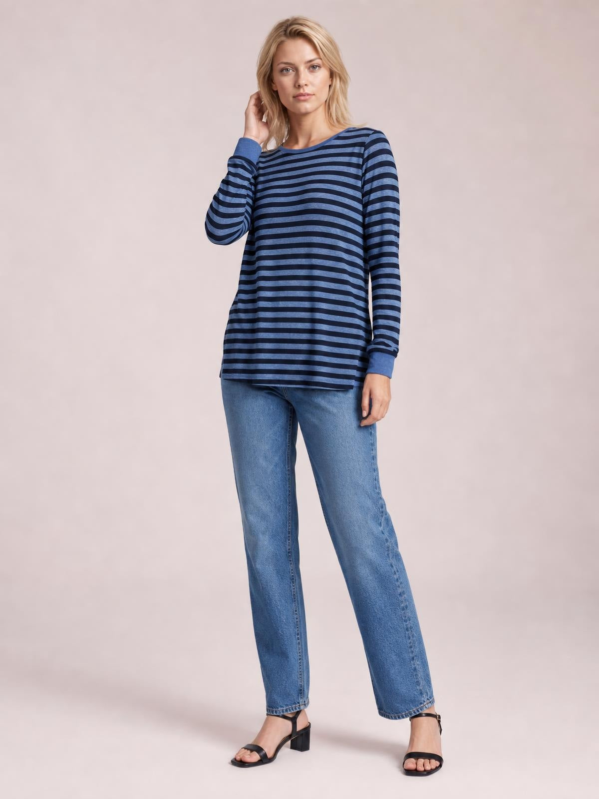 Model poses in a navy and blue striped round neck long sleeve T-shirt with a relaxed straight silhouette and visible side slit detail.