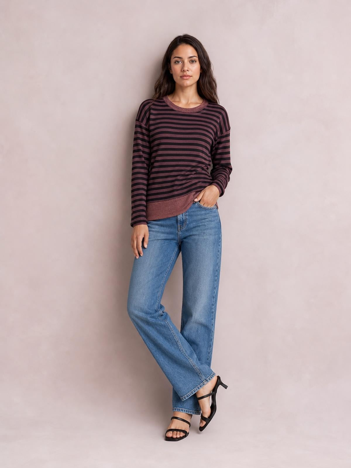 A model poses in a burgundy and black striped round neck long sleeve T-shirt with a relaxed silhouette and visible slit detail at the hem.
