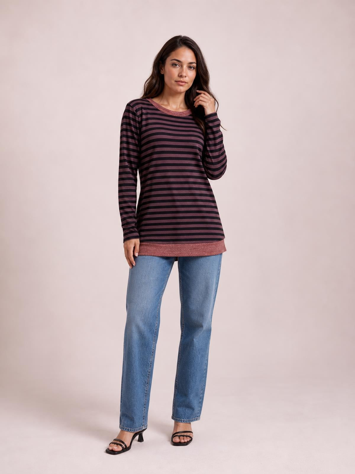 Model poses in a striped round neck long sleeve T-shirt with a relaxed tunic silhouette, dark horizontal stripes, contrast trim, and a visible side slit.