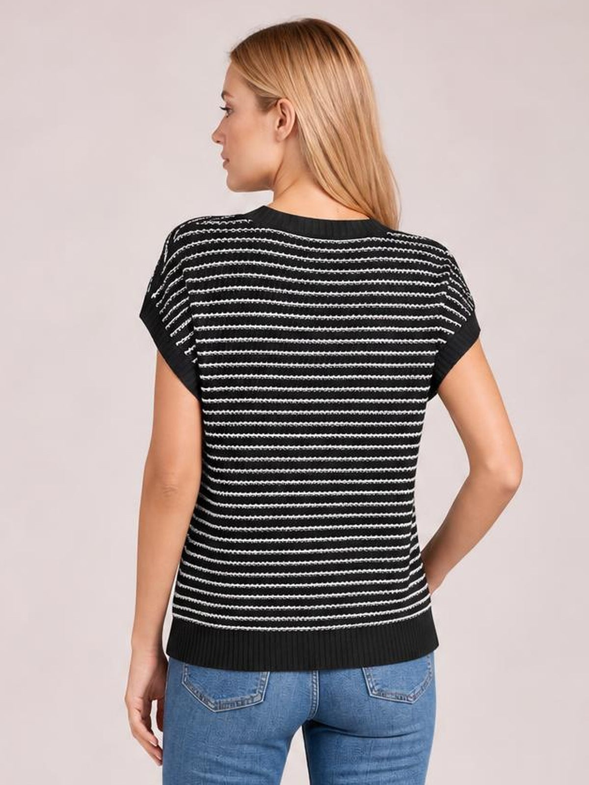 Model shown from the back wearing a black striped round-neck short-sleeve knit top with a relaxed silhouette and ribbed hem, one hand on her hip.