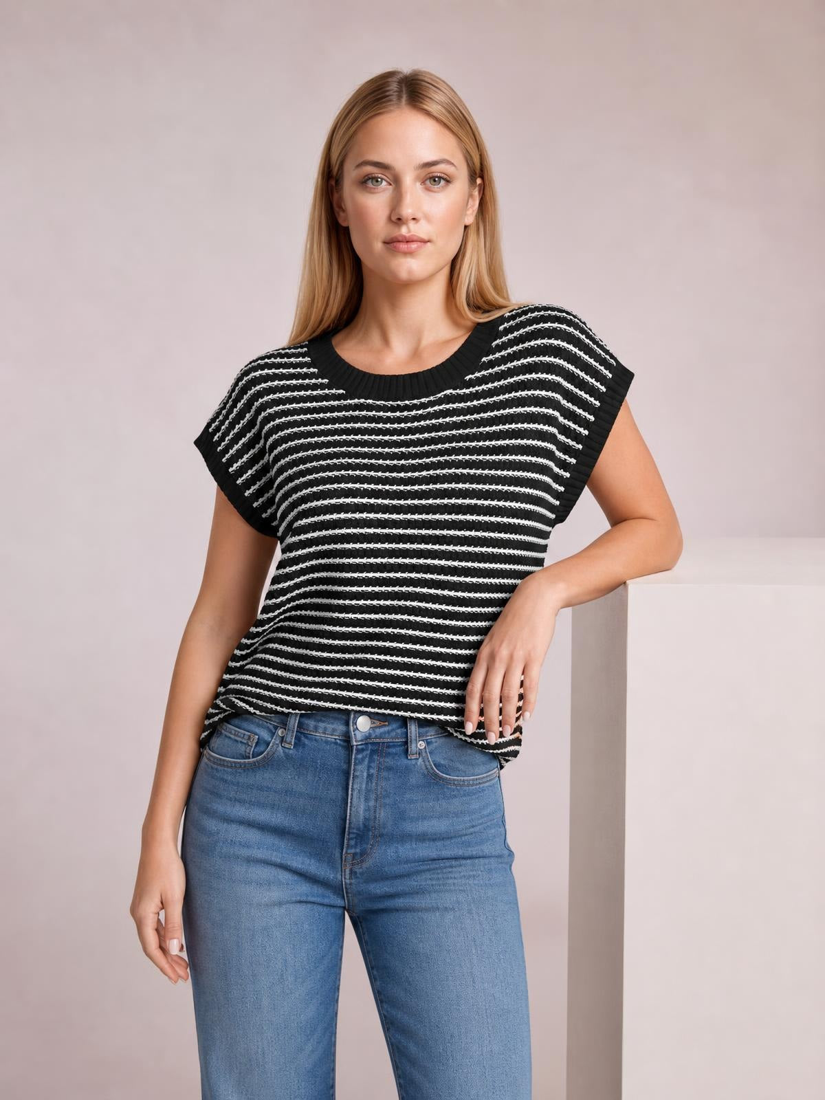 Model poses in a black-and-white striped round neck short sleeve knit top with ribbed trim and a relaxed, straight silhouette.