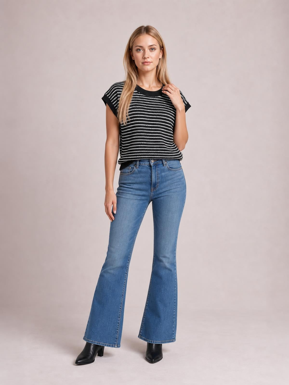 Model poses in a black-and-white striped round neck short sleeve knit top with a relaxed straight silhouette and slightly cropped hem.