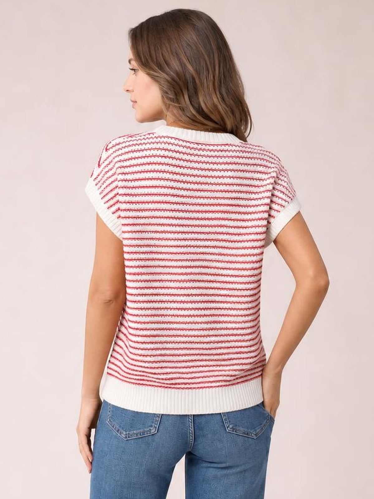 Model shown from behind wearing a white and red striped round-neck short-sleeve knit top with a relaxed silhouette, ribbed trim, and one hand in her pocket.