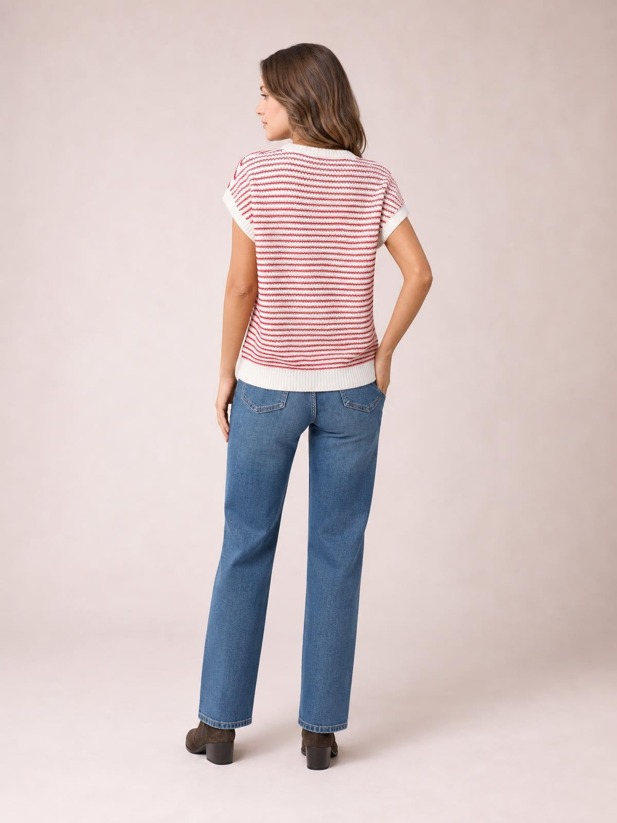 Model shown from behind wears a white knit top with red horizontal stripes, round neck, short sleeves, ribbed trim, and a straight silhouette, posing with one hand on her hip.