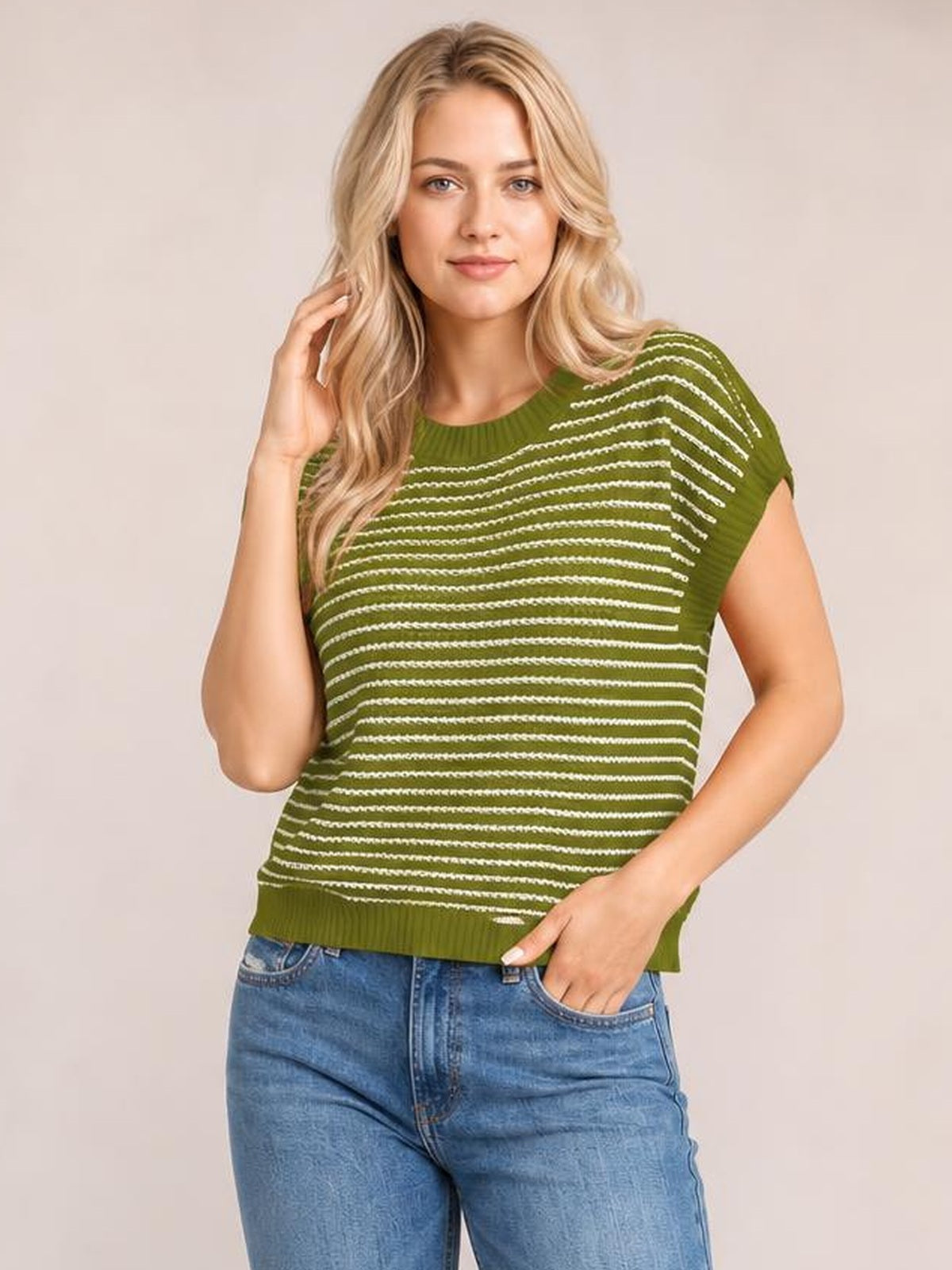 Model wearing a green striped round neck short sleeve knit top with a relaxed silhouette, ribbed neckline and hem, posing with one hand in her jeans pocket.