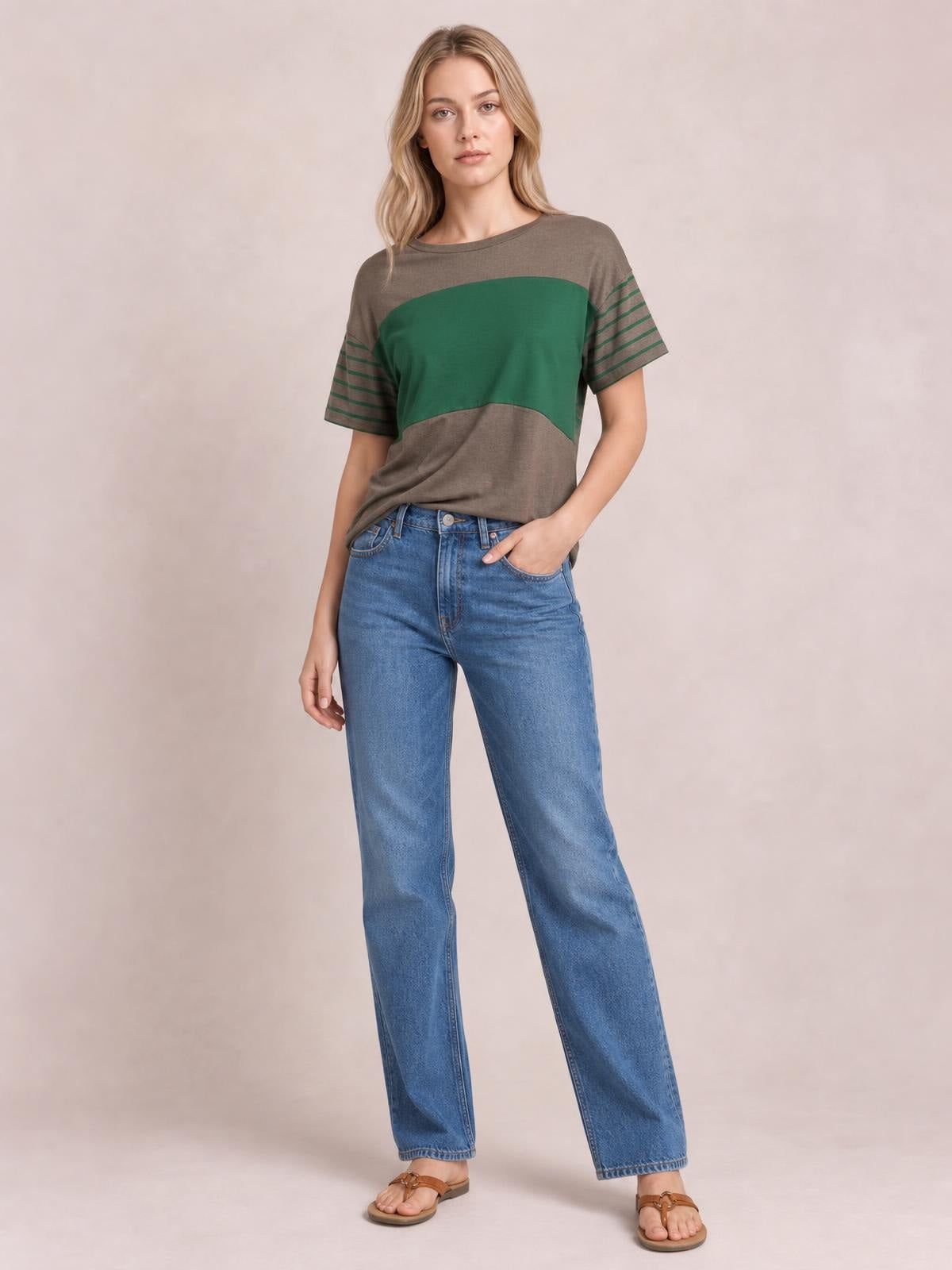 Model poses in a gray and green striped round neck short sleeve T-shirt with a relaxed silhouette and contrasting horizontal sleeve stripes.