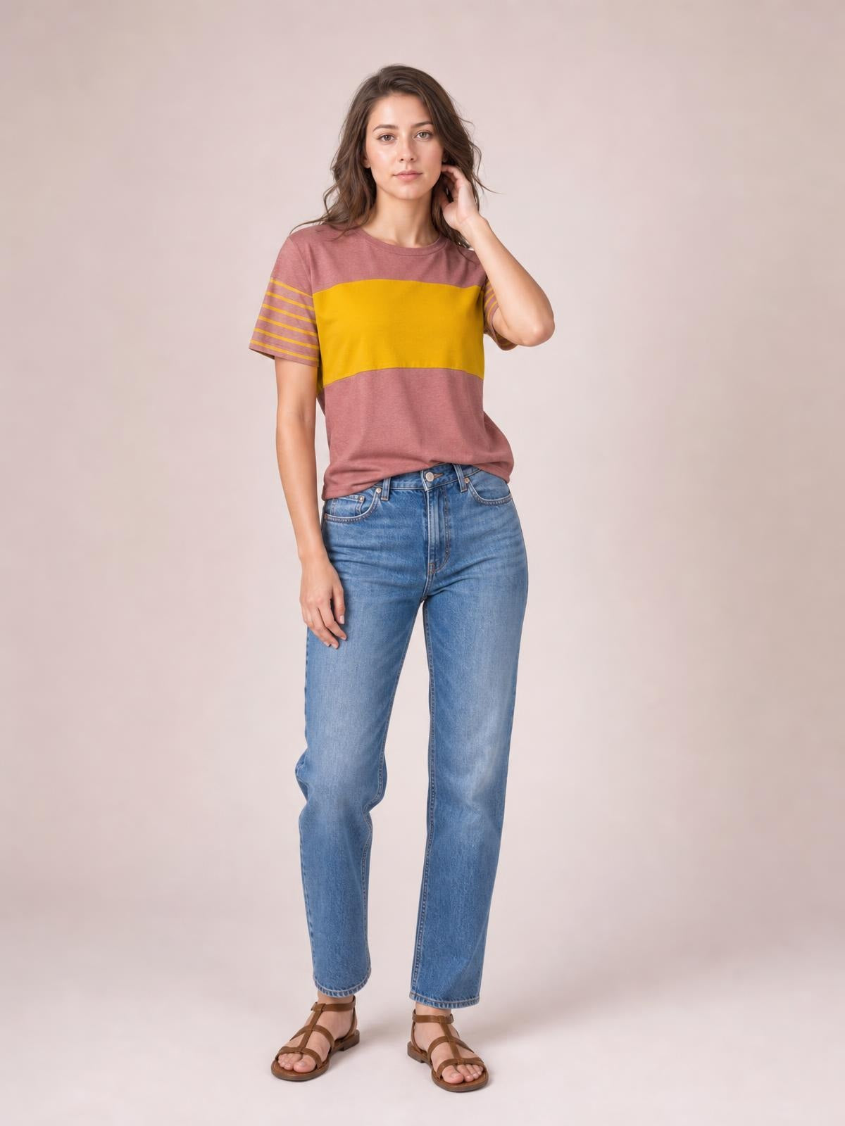 Model poses in a mauve and mustard striped round neck short sleeve T-shirt with a relaxed silhouette and contrasting horizontal sleeve stripes.