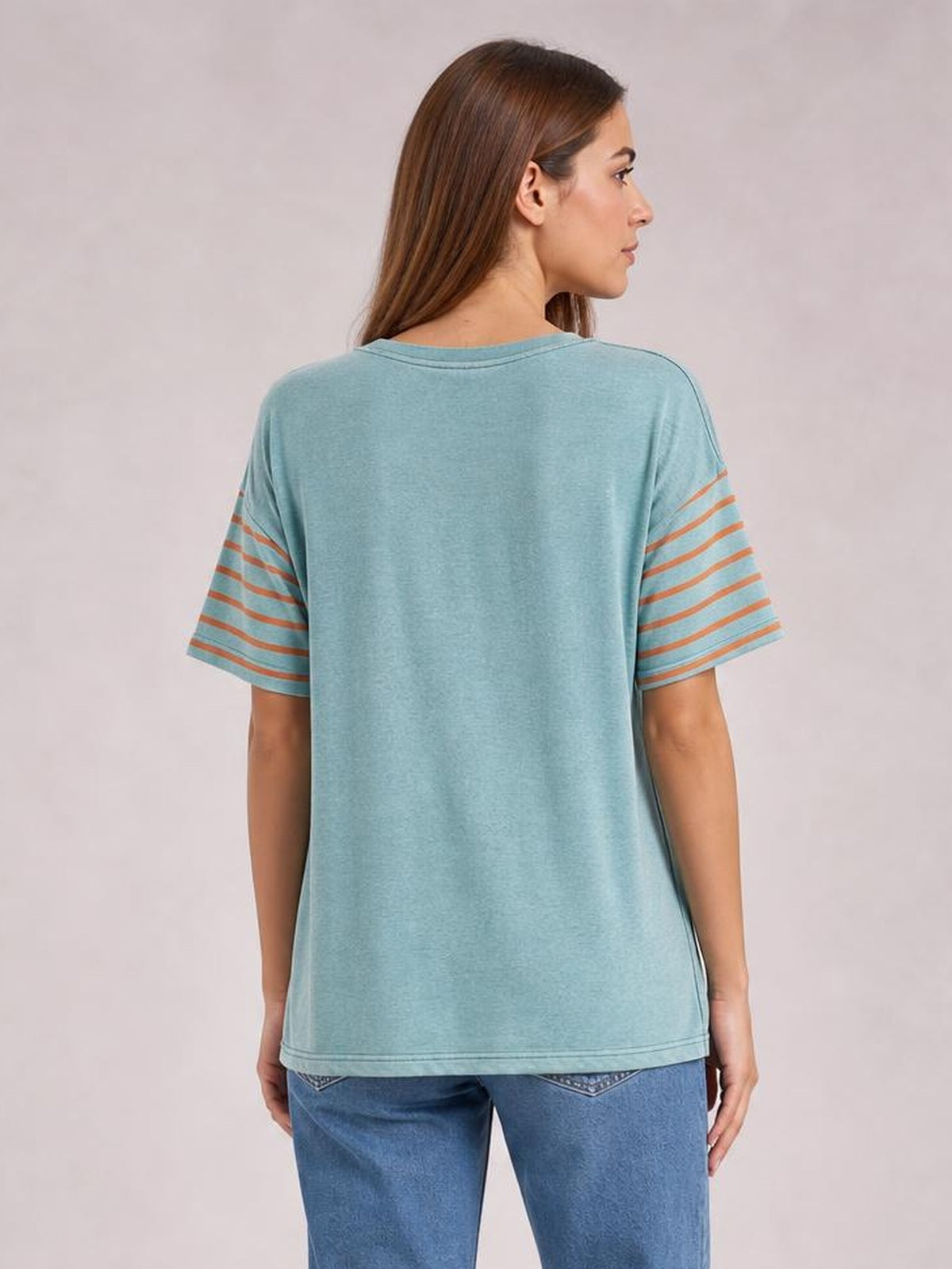 Model faces away wearing a loose aqua striped round-neck short-sleeve T-shirt with contrasting horizontal sleeve stripes and a straight hem.