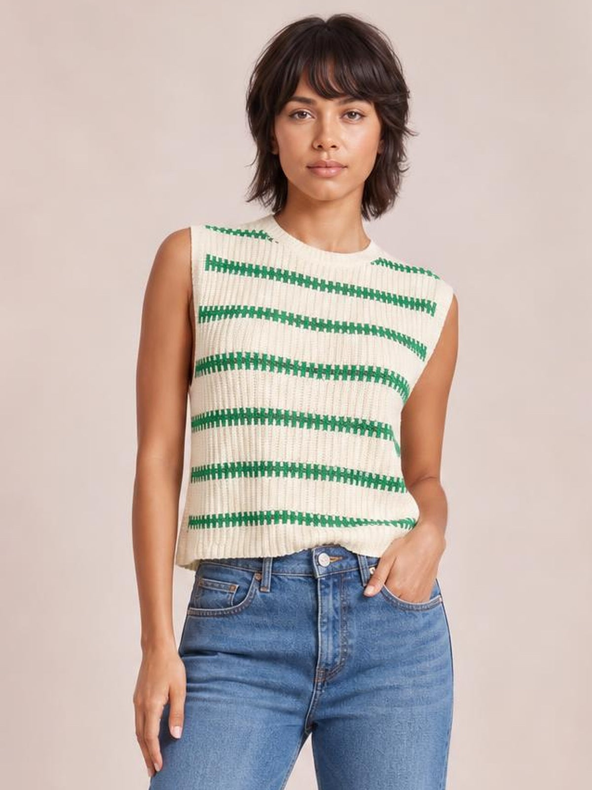 Model wearing a cream striped round neck sweater vest with green horizontal stripes, sleeveless cut, ribbed knit texture, and a relaxed straight silhouette.