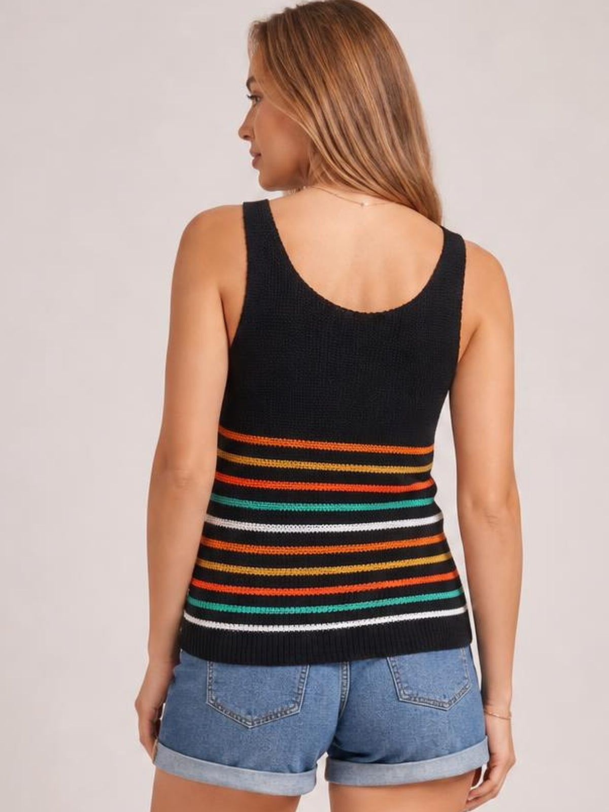 Model shown from behind in a black striped knit tank with wide shoulder straps, a scoop back, colorful horizontal bands, and a relaxed straight silhouette.