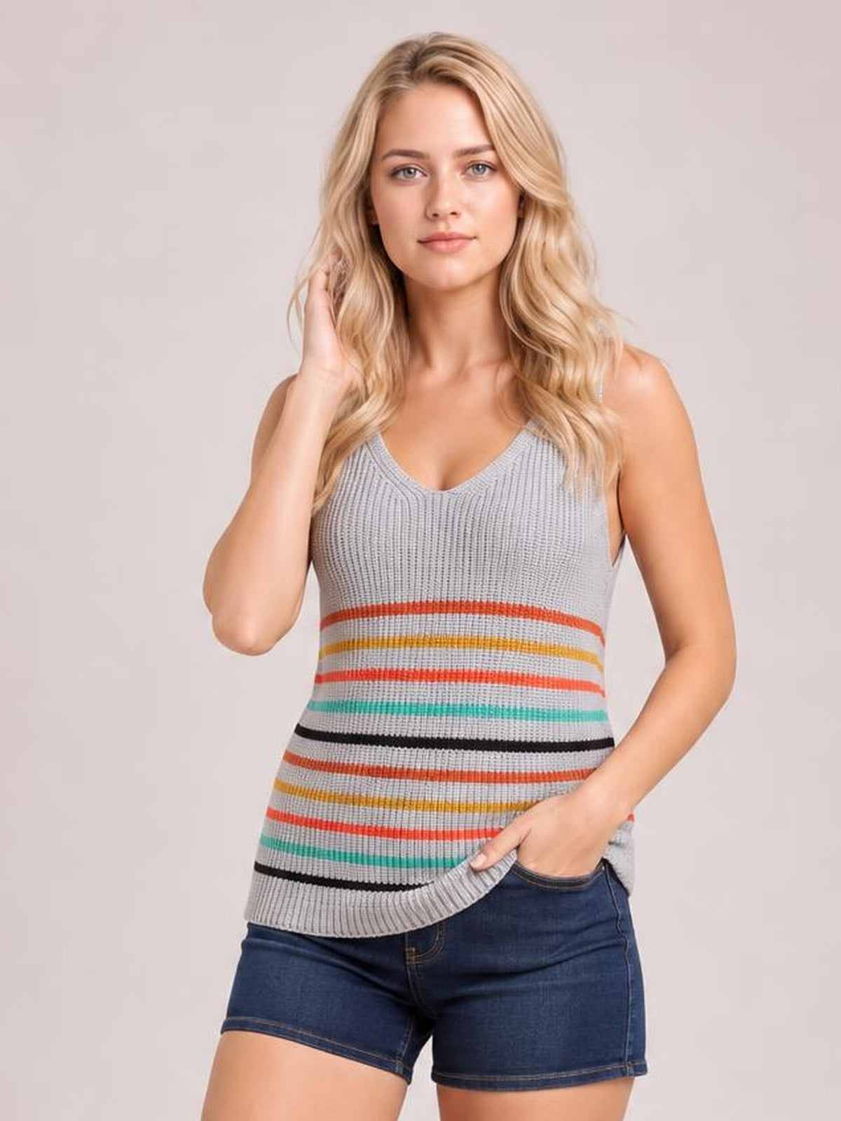 Model touching her hair wears a gray striped V-neck knit tank with multicolor horizontal bands, fitted silhouette, and ribbed construction.