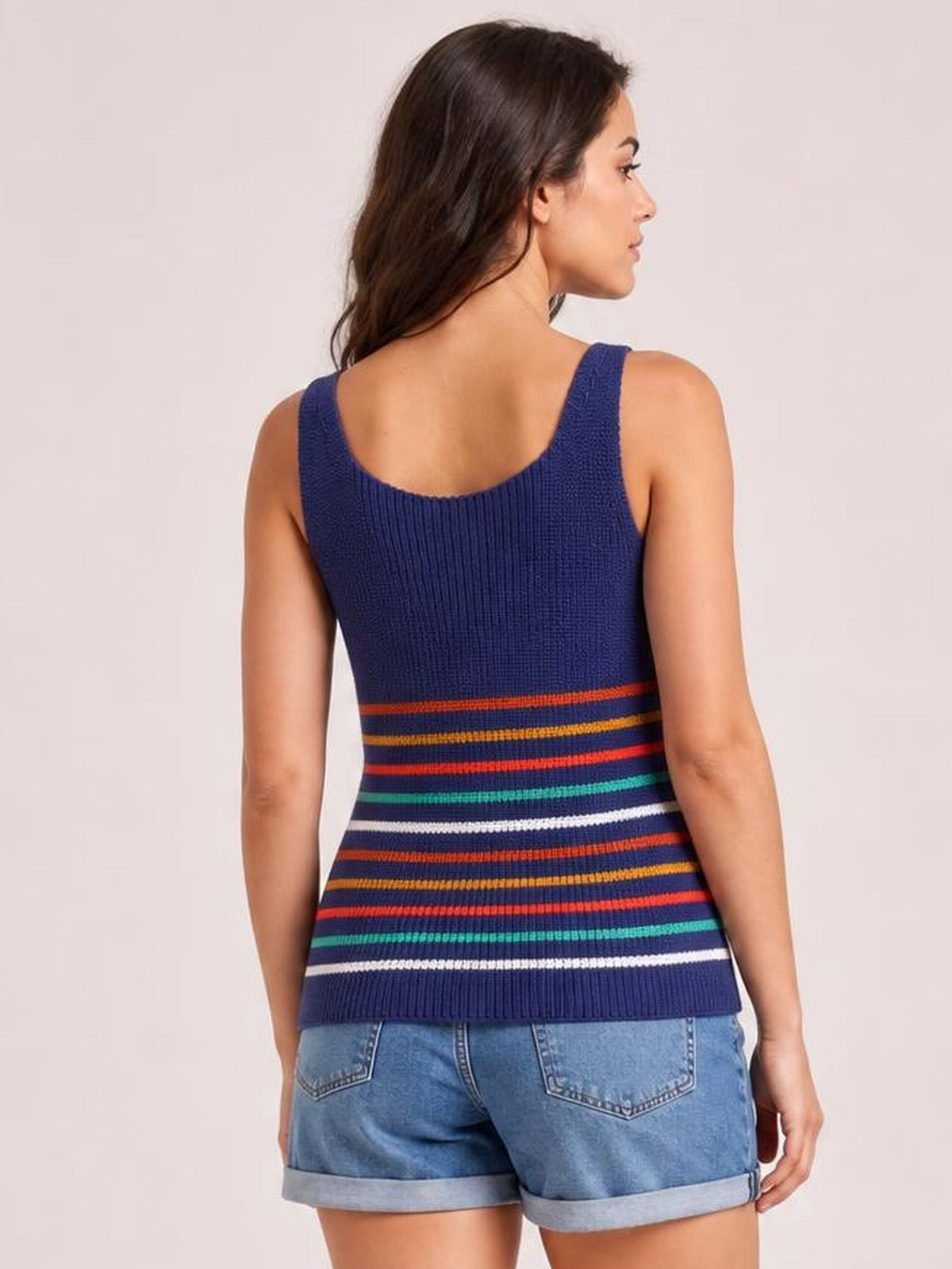 A model stands in a back view wearing a navy knit tank with wide straps, a straight silhouette, and colorful horizontal stripes.