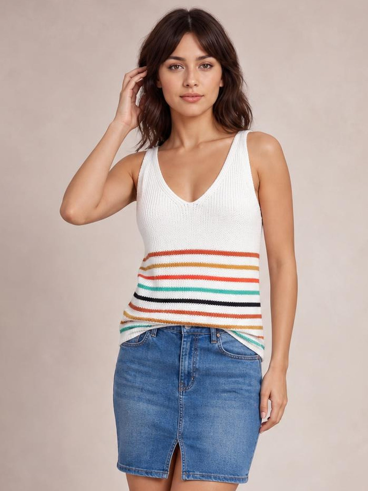 Model poses in a white knit tank with a V-neck, wide shoulder straps, and colorful horizontal stripes across the lower fitted silhouette.