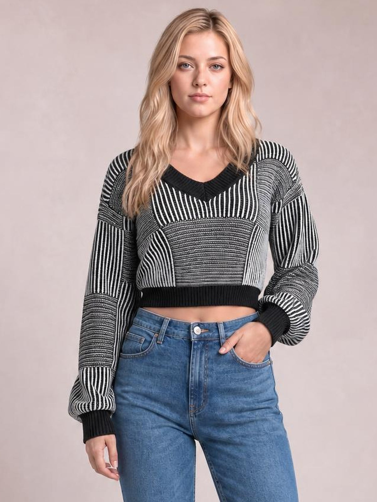 Model wearing a black-and-white striped V-neck long-sleeve sweater with contrasting knit panels, ribbed cuffs and hem, cropped silhouette, and relaxed fit.