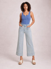 Model stands with hands in the pockets of light blue striped wide-leg cropped jeans, featuring a high waist, front patch pockets, and cuffed hems.