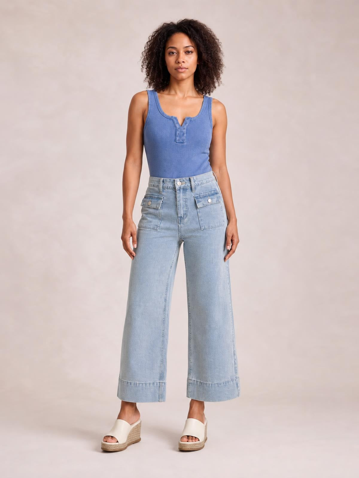 Model stands facing forward in light blue striped wide-leg cropped jeans with a high waist, button closure, front pockets, and cuffed hems.