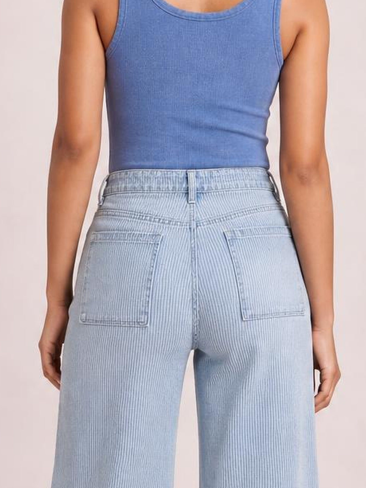 A model wears light-blue striped wide-leg cropped jeans with a structured waistband, belt loops, and two large back patch pockets.