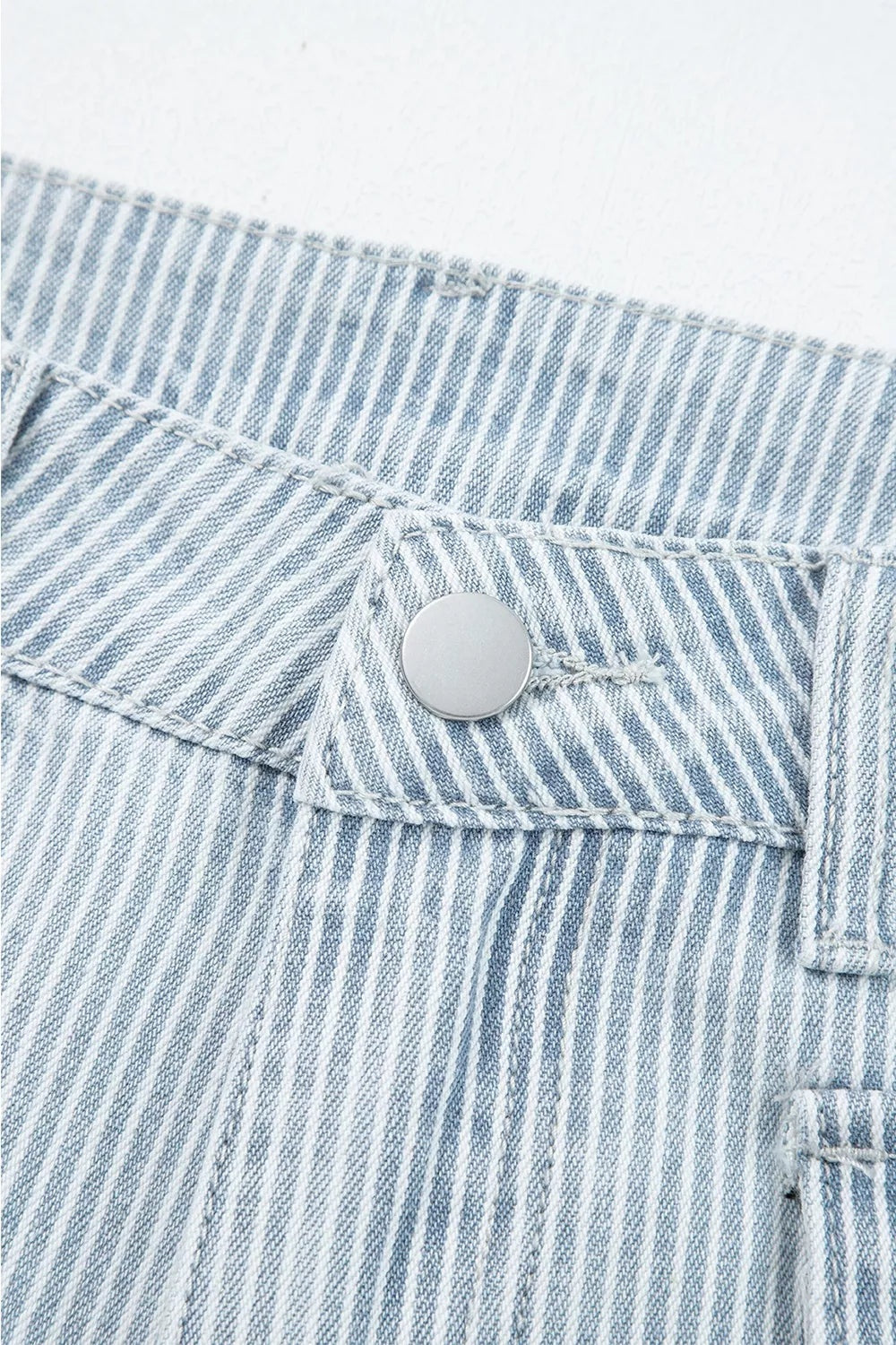Close-up of light blue and white striped wide-leg cropped jeans showing the waistband, button closure, belt loop, pocket stitching, and denim construction.