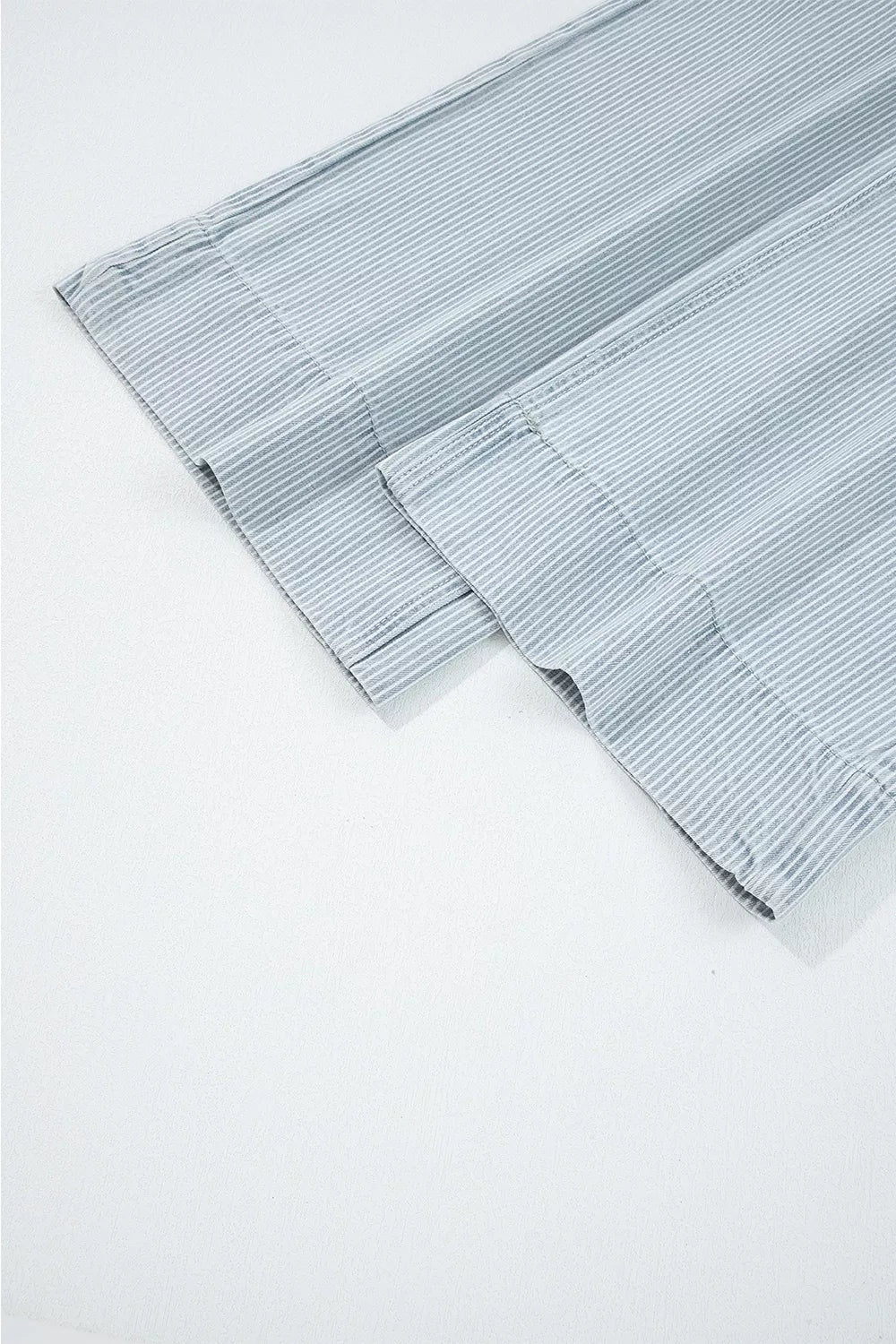 Close-up of striped gray wide-leg cropped jeans showing fine vertical lines, a clean cropped hem, and visible seam construction.