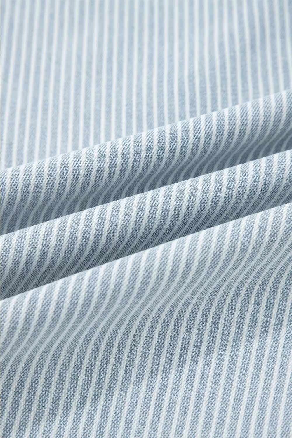 Close-up of light blue and white striped denim fabric showing a textured woven construction for wide-leg cropped jeans.