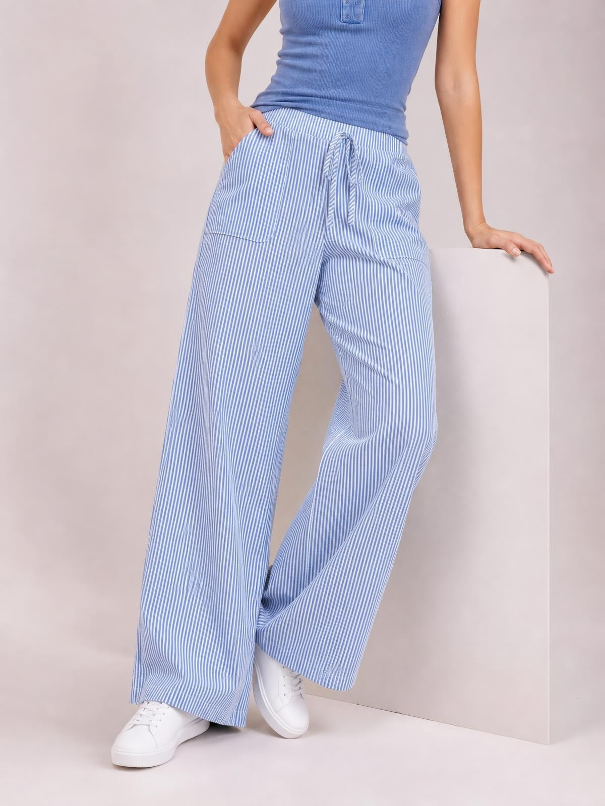 Model wearing light blue and white striped wide leg pants with an elastic drawstring waist, angled front pockets, and a relaxed flowing silhouette.