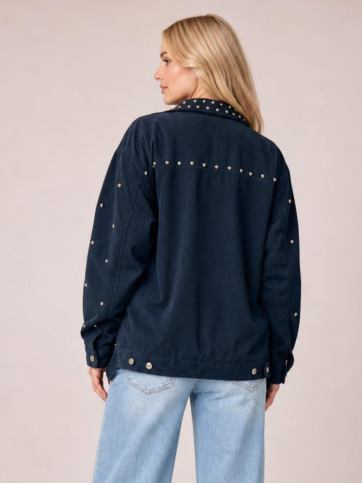 Model shown from the back wears a dark navy corduroy button-up jacket with a collared neck, relaxed silhouette, pockets, and silver stud embellishments.