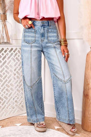 Model poses with one hand in the pocket, wearing light-wash studded detail jeans with a high waist, wide legs, patch pockets, and paneled construction.