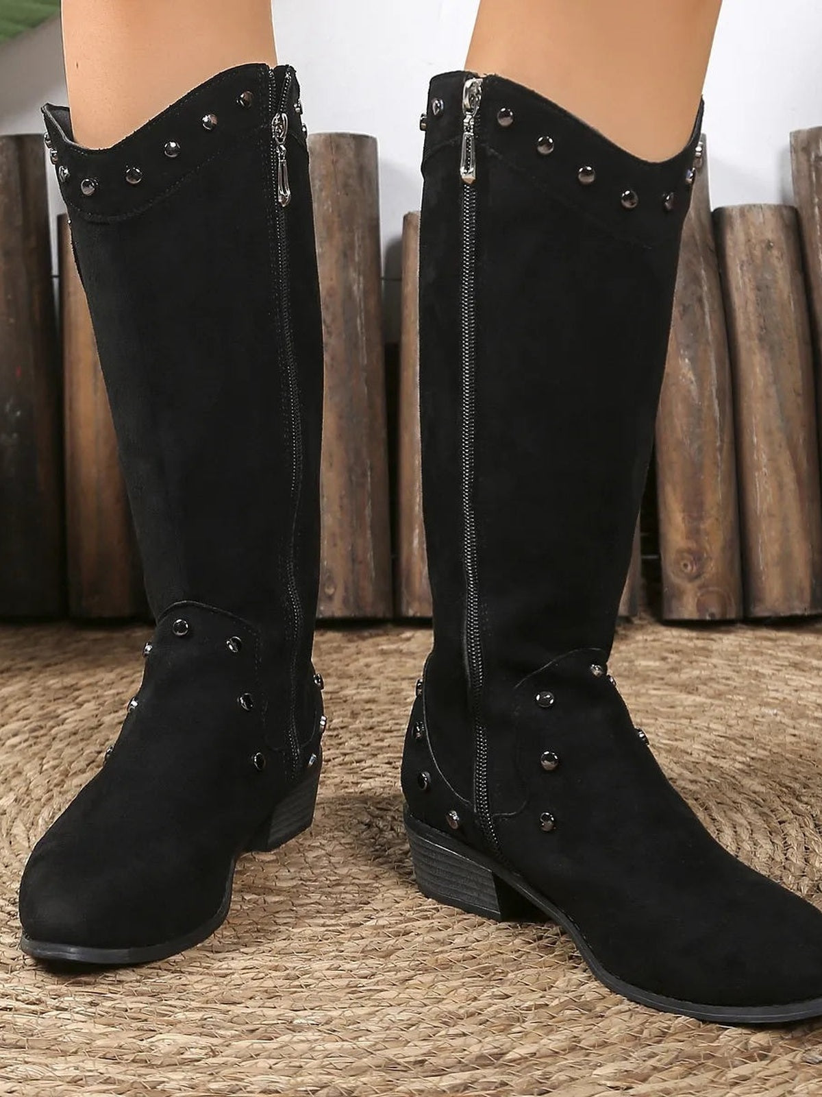 Visible model wears black studded mid-calf boots with side zipper closures, rounded toes, decorative paneling, and low stacked heels.