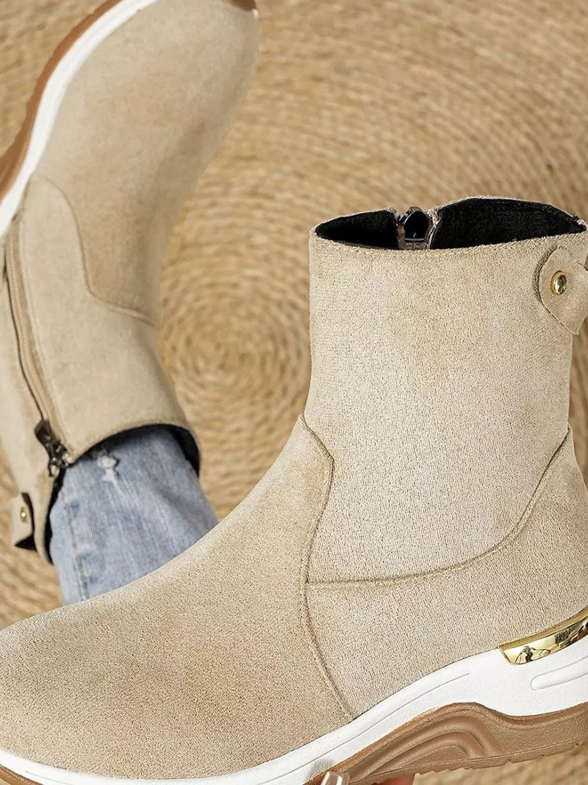 Beige suede ankle boots feature a rounded toe, stitched panel construction, side zippers, mid-height wedge heels, and textured rubber soles.
