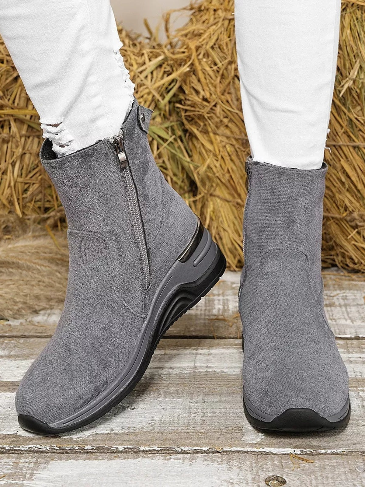 A model stands in gray suede ankle boots with wedge heels, side zippers, rounded toes, and thick black rubber soles.