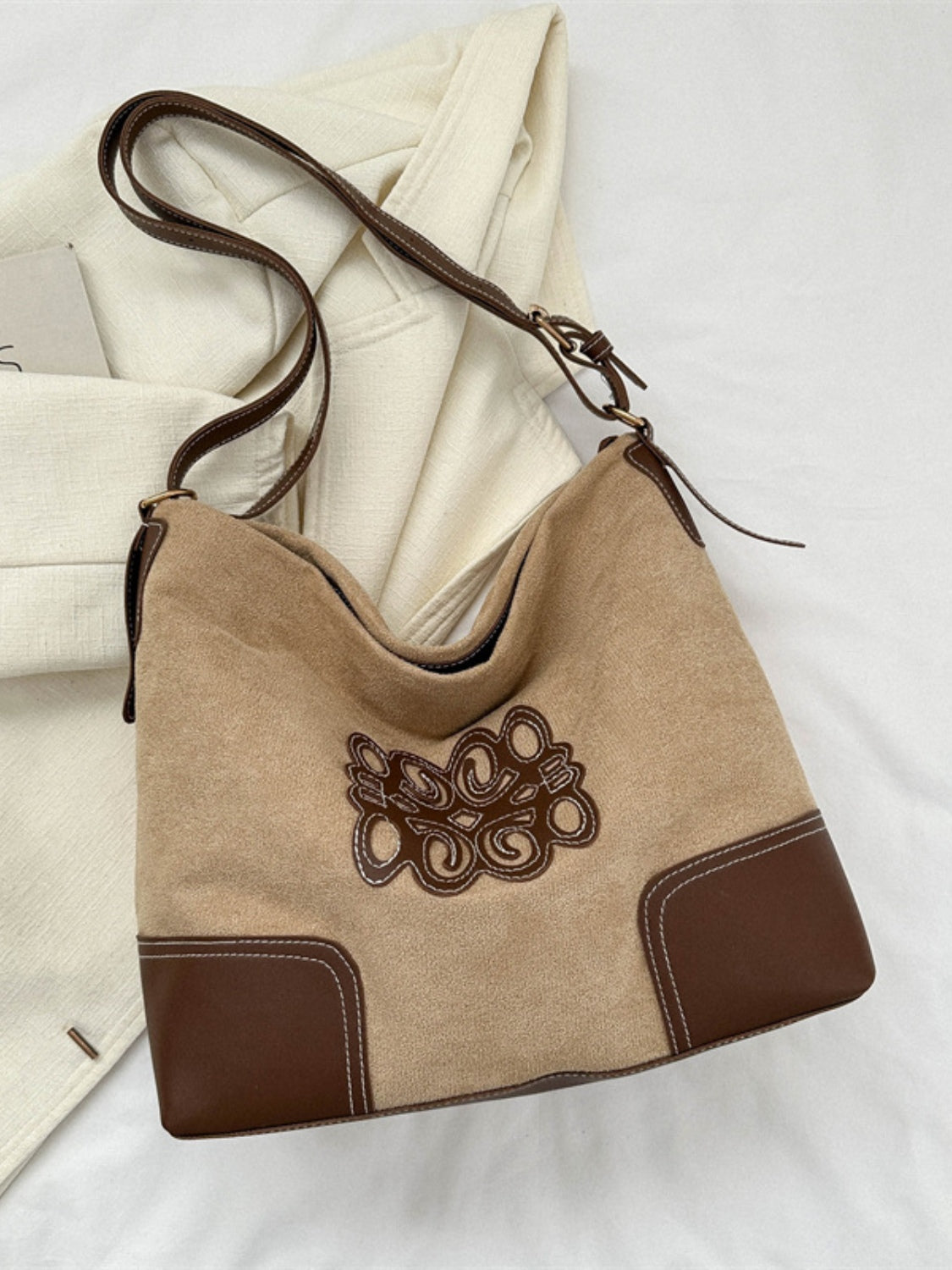 Beige suede patch tote bag with a softly structured silhouette, brown PU leather corner panels, decorative stitched detailing, and an adjustable shoulder strap.