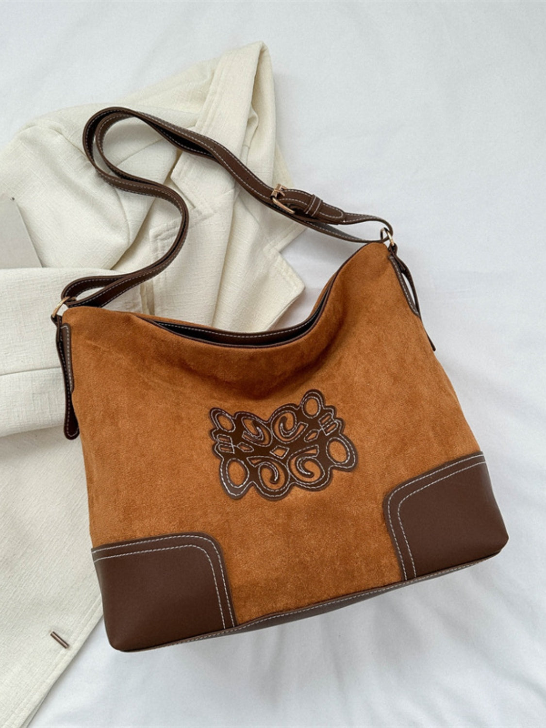 Medium cognac suede patch tote bag with a relaxed silhouette, brown PU leather lower panels, decorative stitched front detail, and an adjustable strap.