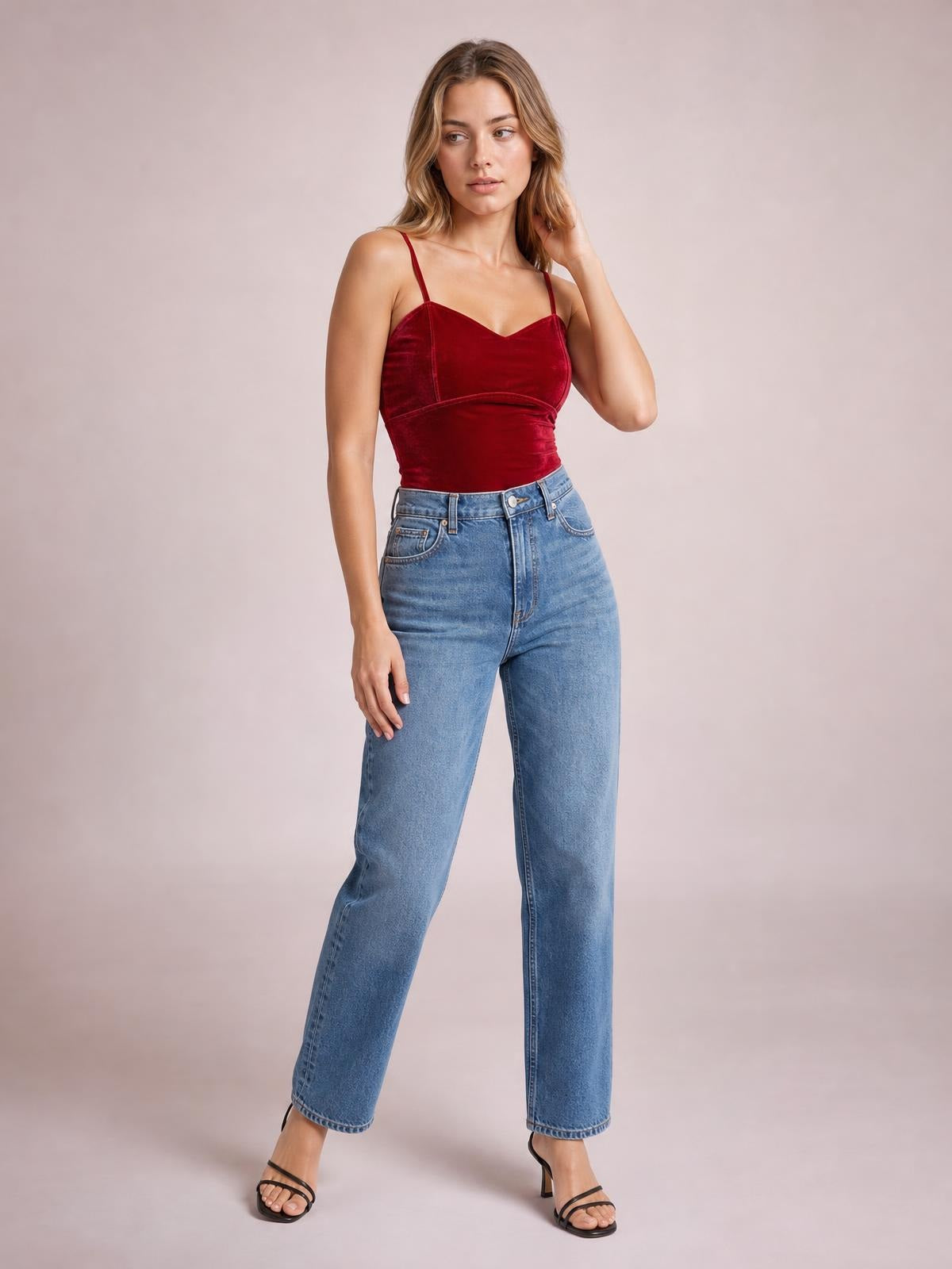 A model poses in a burgundy sweetheart-neck cropped cami with thin straps, a fitted silhouette, and a defined underbust seam, touching her hair.