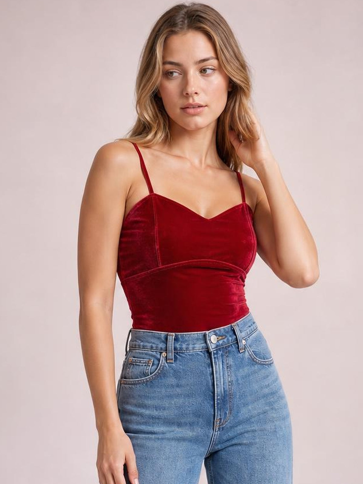 Model poses with one hand in her hair wearing a deep red sweetheart-neck cropped cami with thin straps, a fitted silhouette, and a seamed underbust.