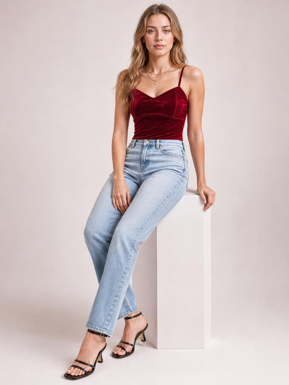 A seated model wears a burgundy sweetheart-neck cropped cami with thin shoulder straps, a fitted silhouette, and visible seamed bust construction.