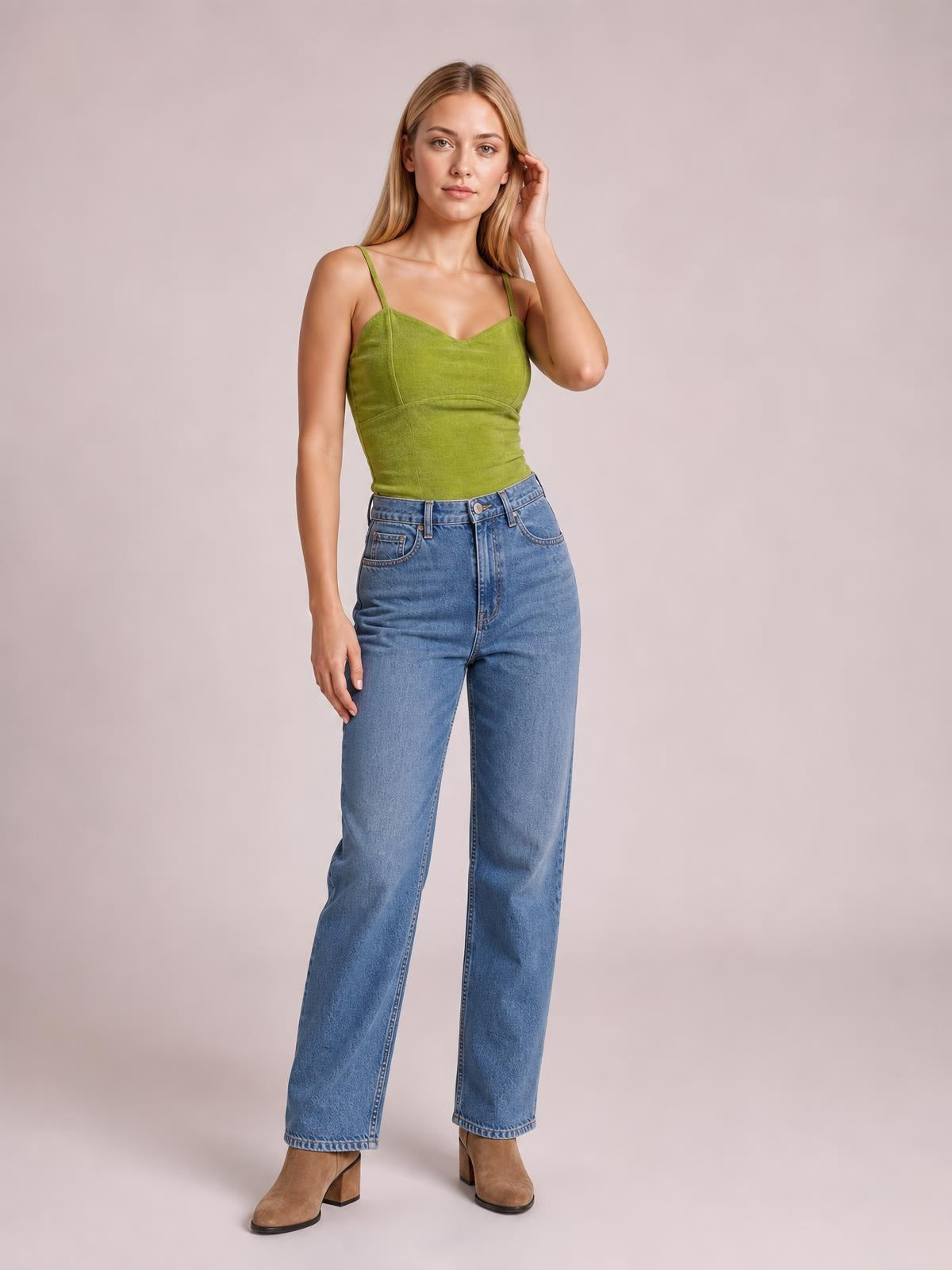 A model poses in a fitted olive-green sweetheart neck cropped cami with thin straps and visible seamed construction, paired with high-waisted jeans.