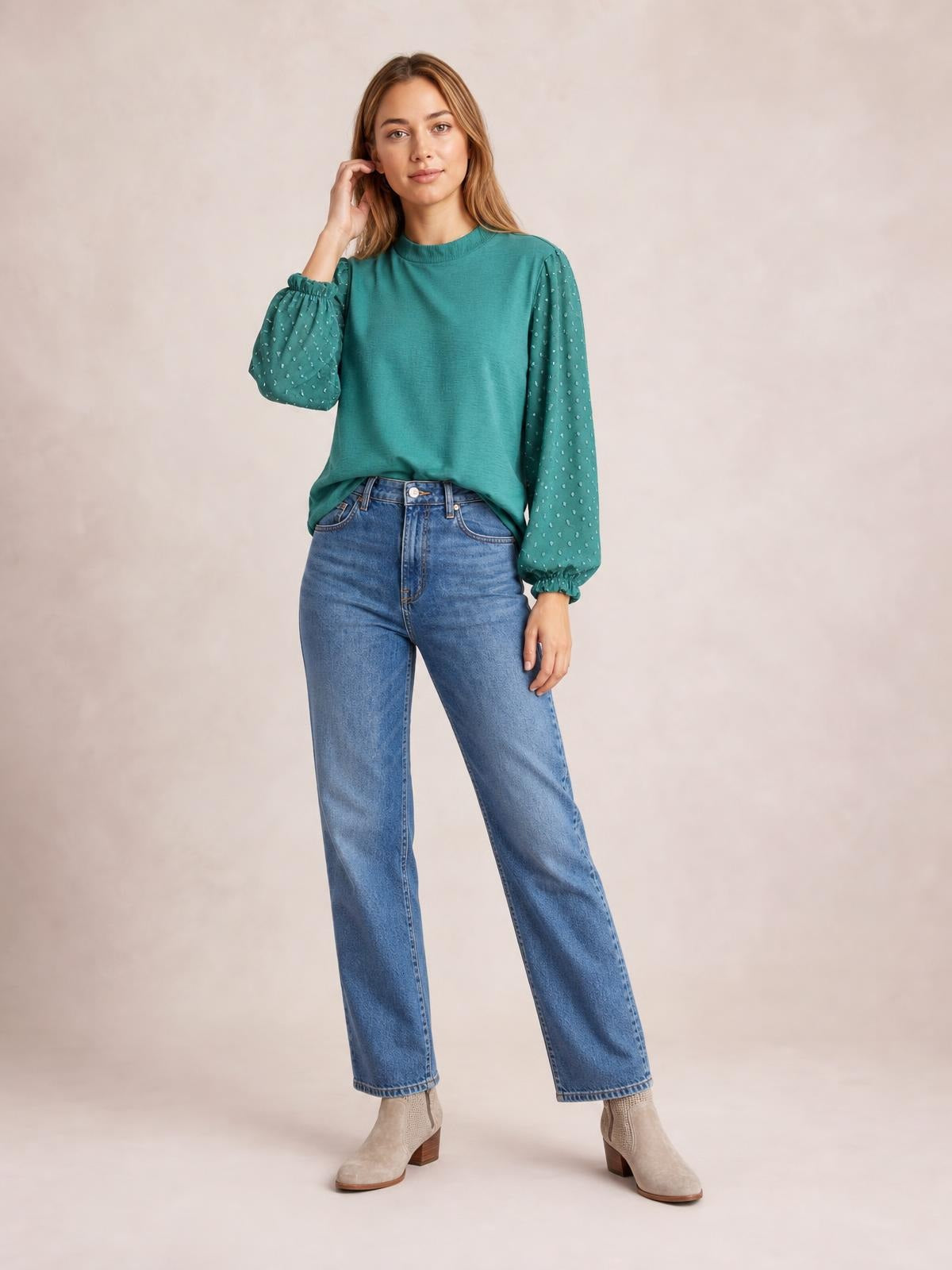 A model poses in a teal Swiss dot blouse with a mock neck, relaxed silhouette, and voluminous balloon sleeves gathered at the cuffs.