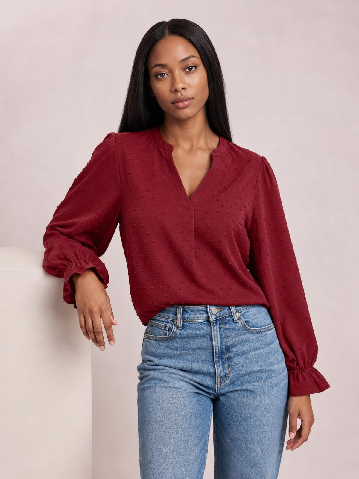 Model wears a burgundy Swiss dot blouse with a notched V-neck, long flounce sleeves, gathered cuffs, and a relaxed straight silhouette.