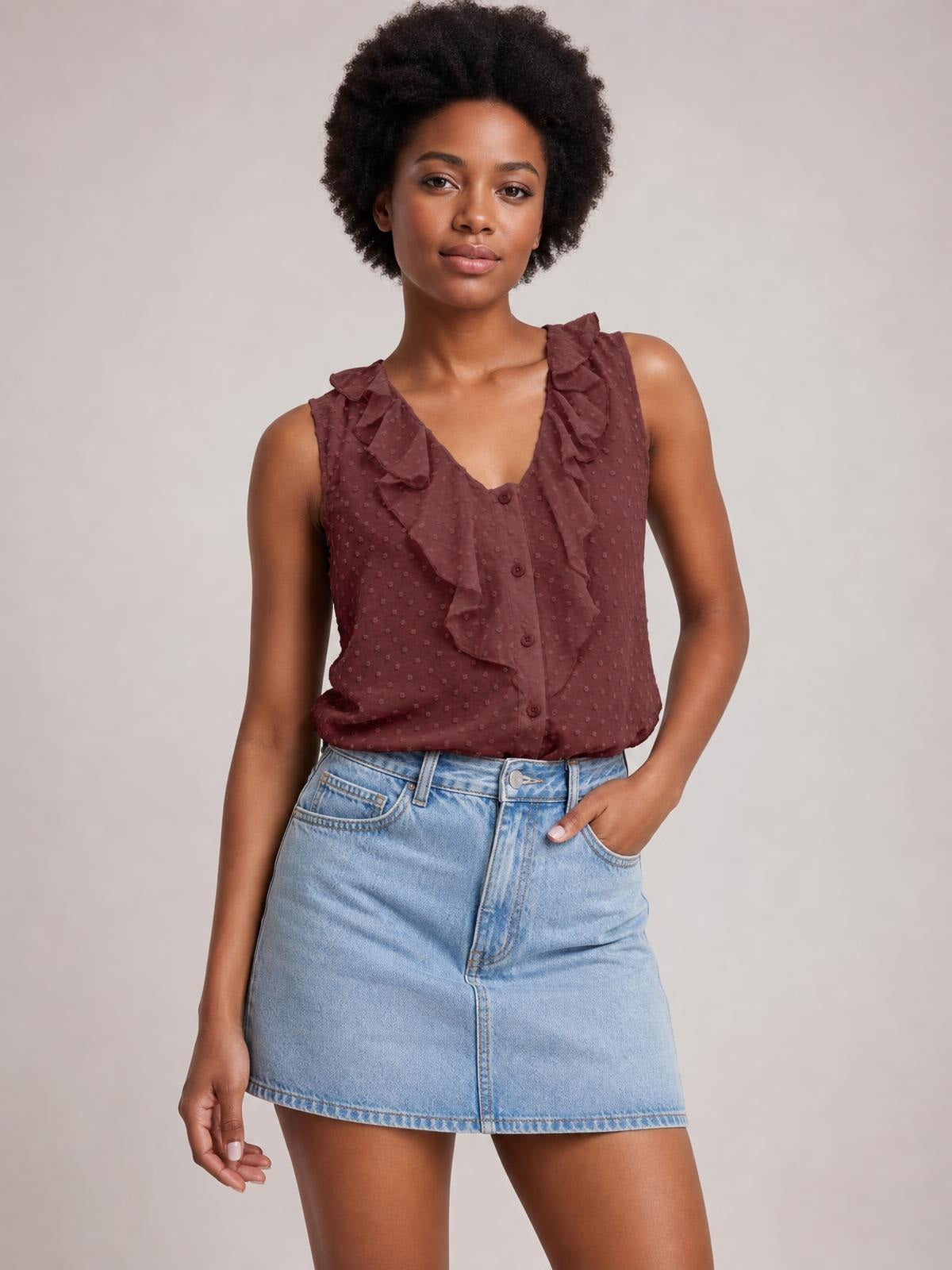 A model poses in a burgundy Swiss dot tank with ruffled wide straps, a V-neck, button-front construction, and a relaxed straight silhouette.