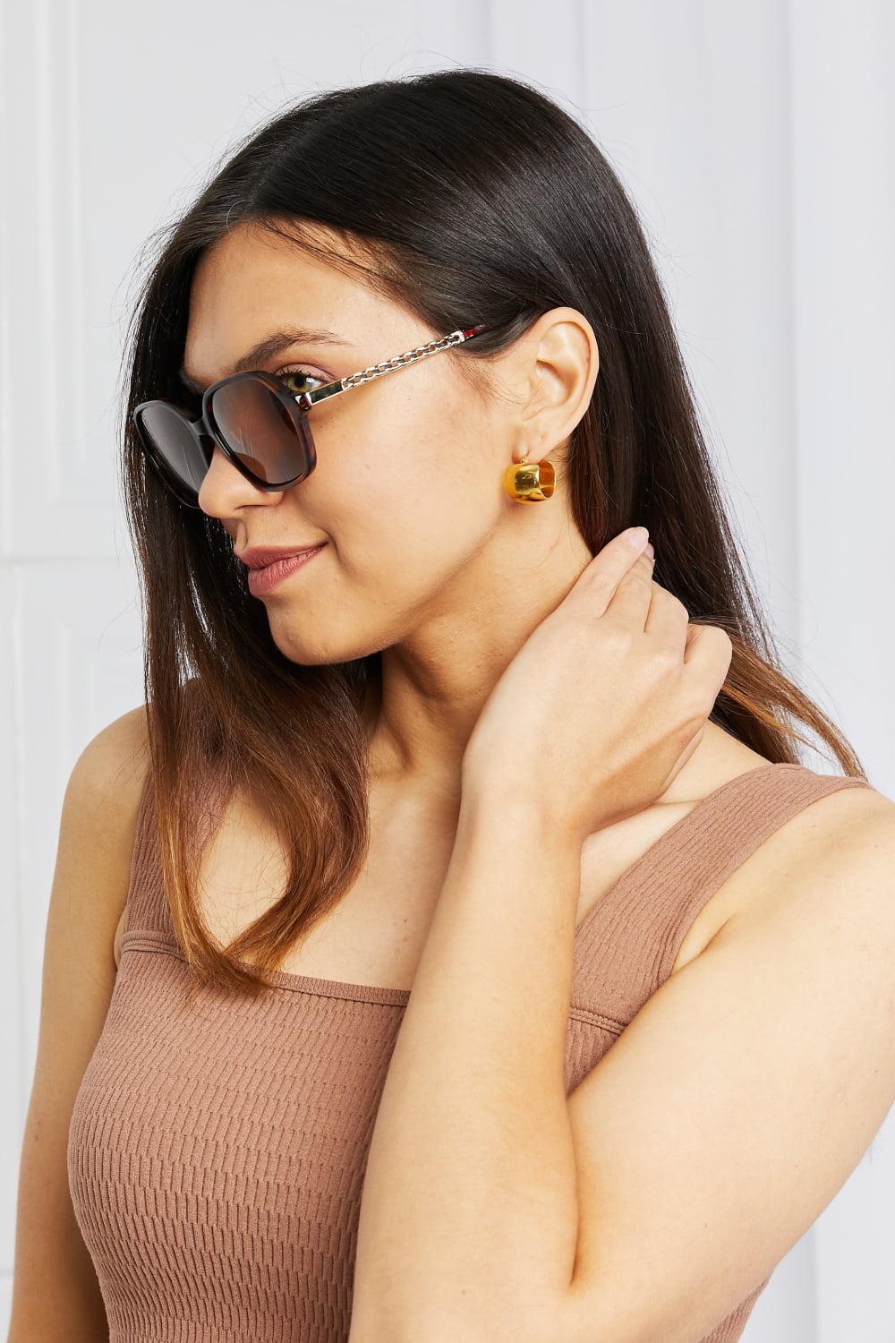 Model poses in profile wearing brown full-rim square sunglasses with warm-toned TAC polarized lenses and sculpted acetate frames with metal-acetate temples.
