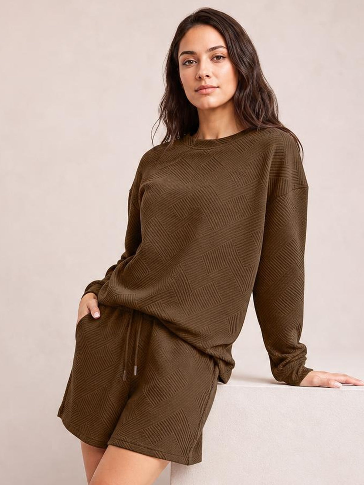 Model poses in a brown textured long sleeve top and matching relaxed drawstring shorts set, featuring an oversized silhouette and geometric pattern.