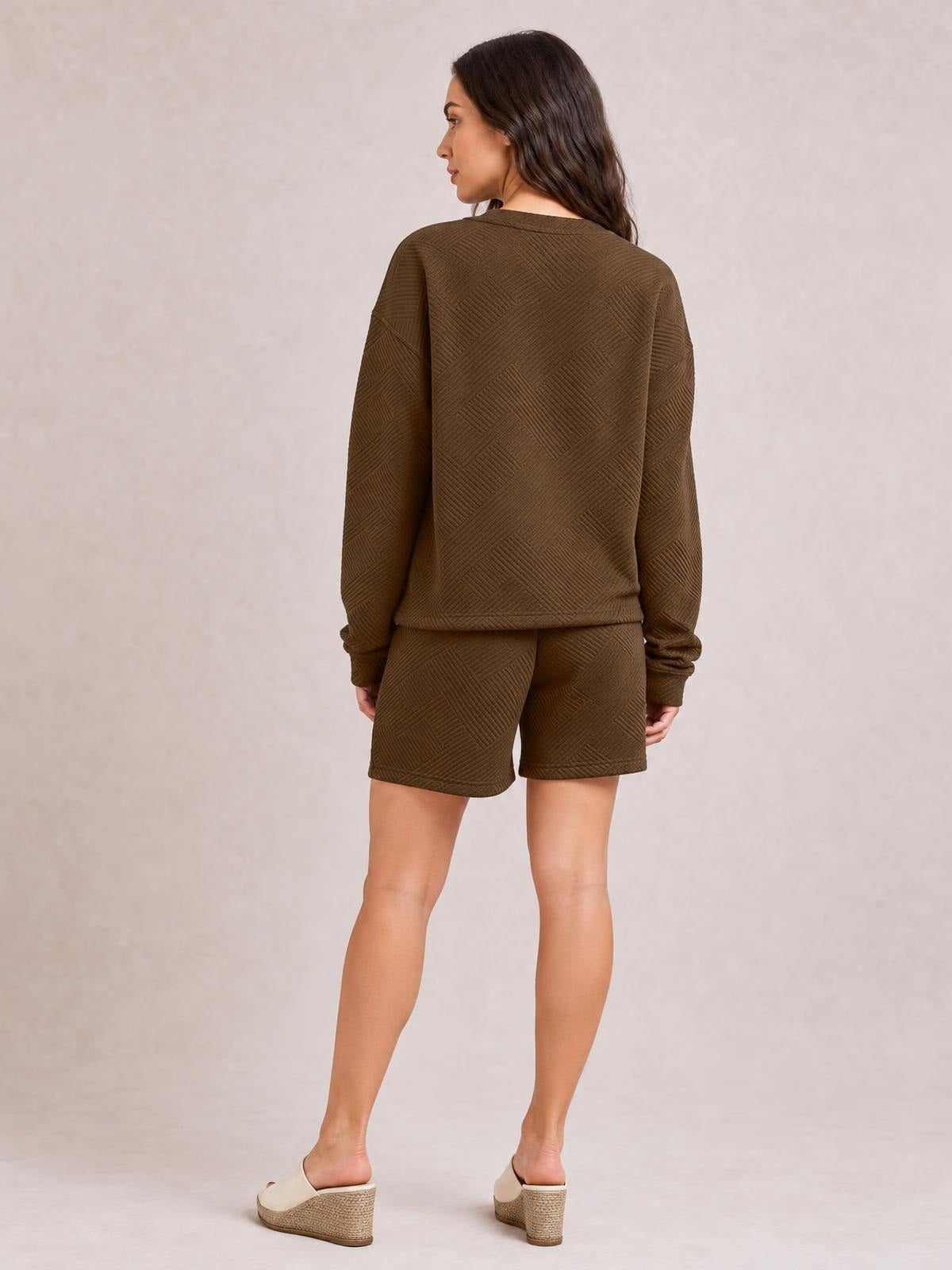 A woman stands in a back view wearing a relaxed brown textured long sleeve top with matching drawstring shorts and a comfortable loose silhouette.