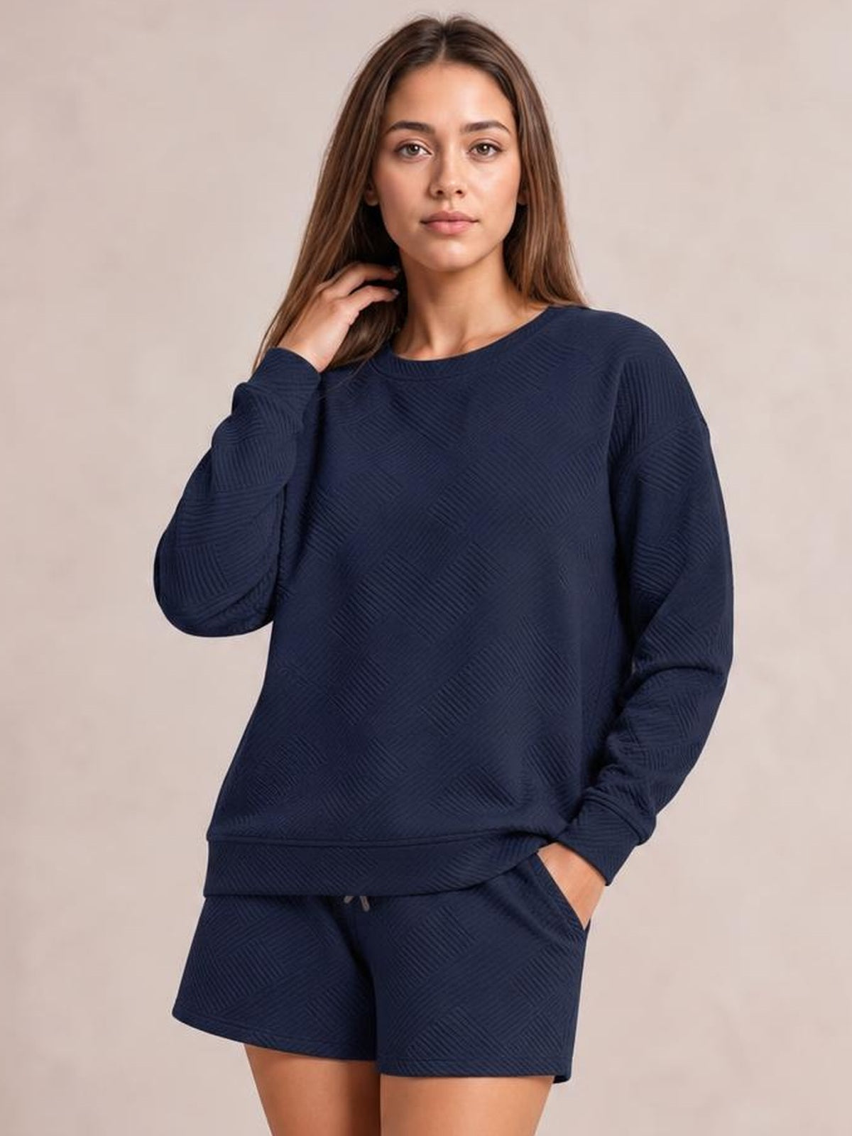 Model poses in a navy textured long sleeve top and drawstring shorts set with a relaxed fit, ribbed cuffs, elastic waistband, and side pockets.