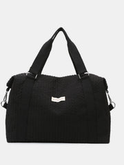 Large black textured Oxford cloth travel bag with a softly structured silhouette, wide top handles, reinforced straps, and a detachable shoulder strap.
