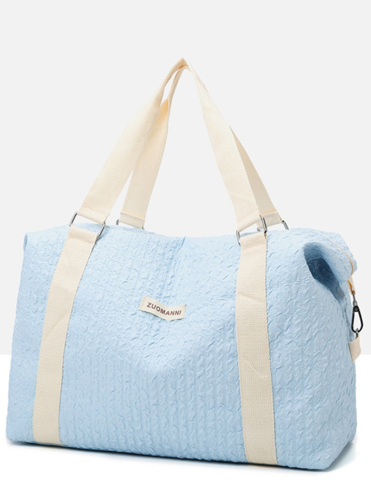 A large light blue textured Oxford cloth travel bag with a softly structured silhouette, wide cream webbing handles, and reinforced side hardware.