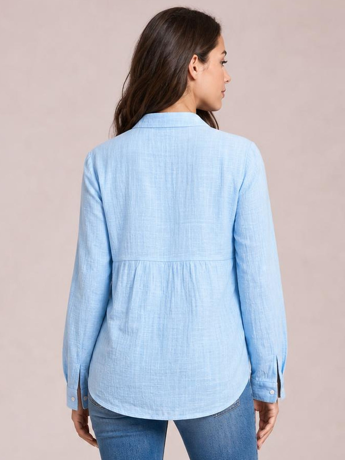 Model shown from behind wearing a light blue textured collared shirt with long sleeves, a relaxed silhouette, back seam detail, and a curved hem.